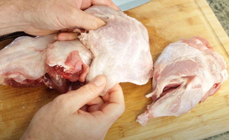 Man slicing nutria meat on a cutting board